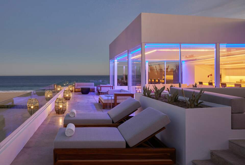 Modern ocean-front home with blue lighting and clear skies